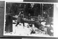 Children with crosscut saw cutting large log in snow