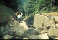 Three men examining site of flood?  Rocky stream with concrete abutment