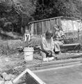 Jean Mountaingrove and another women stripping a log of bark