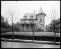 Exterior of Honeyman Home, Portland. House with tower on small hill. Three leafless trees along sidewalk in foreground.