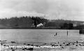 Distant view of smoking mill across the water