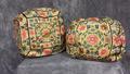 Pair of Armrest Cushions of imperial yellow silk satin heavily embroidered with multi-colored silks of peony, lotus, endless knot, bat, swastika, and butterfly framed in consecutive squares of dark blue satin stitch