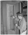 Student examining a broken glass door, 1954