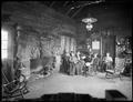 Interior of Cloud Cap Inn. 3 men and 3 women seated to right of stone fireplace.