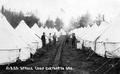 Men standing between rows of tents