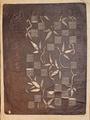 Paper cut art of brown paper in a vine with elongated leaves and a check patterned ground