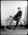 Studio photo of man on bicycle equipped with round steering wheel.