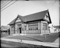 Exterior of brick and timber building, Gresham Library. Sidewalk in foreground, houses in background.