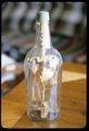 11 x 5 inch whiskey bottle with carvings inside (including 27 people): with bows and arrows, 1 person with an axe, 1 cross, 1 tree/fan, 1 yoke with hanging links