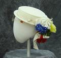 Sailor-style hat of white straw with velvet ribbon and artificial flowers on back