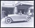 Northwest Auto Co., 5 men sitting in 4 door convertible, in front of hotel entrance.