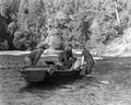 Two men and Wanda Gifford with boat in river