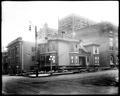 Wood house ready for moving on site of Journal Building, Broadway and Yamhill, Portland. Site surrounded by YWCA and other buildings.