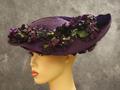 Hat of purple straw with halo of fabric violets and accent swath of purple velvet