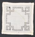 Doily of white linen with drawn-work band with intersecting squares that follows the outer edge
