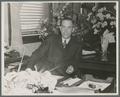 A. L. Strand seated at desk, circa 1945