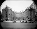 Elevated front view of Portland Hotel, autos on 6th St. in foreground. Landscaped driveway into hotel.