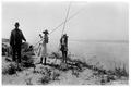 View of dune area of coast, looking south, one man and two women with fishing poles & their catches. Seas perch fishing; surf fishing. One of a series of 3 includes 02-103, 02-127, 02-128