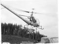 Helicopter lifting off with seed spreader