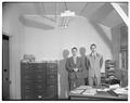 Two unidentified men standing in office