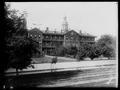 Rear view, St. Mary's Academy, Portland. Trees in yard; fence, street in foreground.