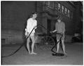 Promotional photo of two OSC co-eds coiling a garden hose