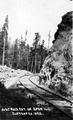 Railroad curving around rock wall.  Man standing to the side