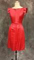 Dress of hot pink (cherry red) silk satin with wide neckline and cap sleeves constructed of a large self-silk bow