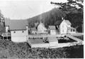 Buildings at Heceta Head showing the barn to the left, the duplex keeper's house in the center and the head lighthouse keeper's single residence to the right.  The chicken house is shown in the foreground.