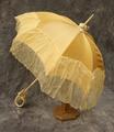 Parasol of gold woven silk trimmed at the end with pale yellow silk chiffon that drapes over the edge