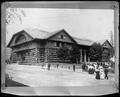 Exterior view of Forestry Building on grounds of Lewis & Clark Exposition, Portland. Front lawn and street in foreground, with parked autos.