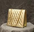 Messenger bag of quilted gold faux leather with gold chain handle