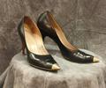 Pumps of black leather with pointed toe capped in gold metal cone