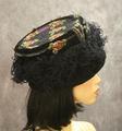 Toque-style hat of black velvet embellished around the sides with ostrich feathers