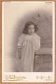 Little girl with dark curly hair wearing a silky gown with lace around the bodice